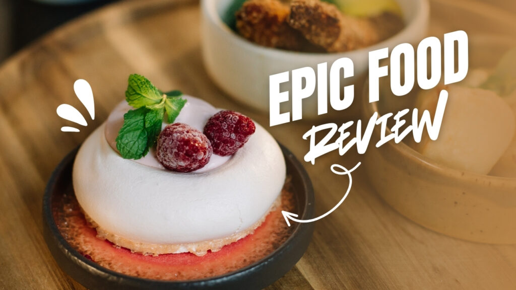 Delicious dessert topped with whipped cream, raspberries, and mint leaves on a wooden table, with text ‘Epic Food Review’ in bold white lettering.