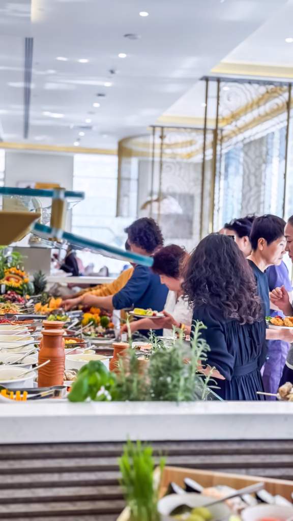 Guests lining up at a vibrant buffet counter filled with fresh ingredients and gourmet dishes, captured by photographers of Dubai—an example of how to become a photographer in Dubai by mastering candid food and lifestyle moments.