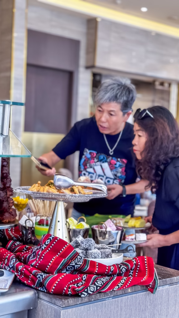 Two guests at a luxury Dubai buffet selecting food, with Middle Eastern desserts and colorful decor in the foreground—an authentic capture by photographers of Dubai, perfect for showcasing how to become a photographer in Dubai through candid culinary moments.